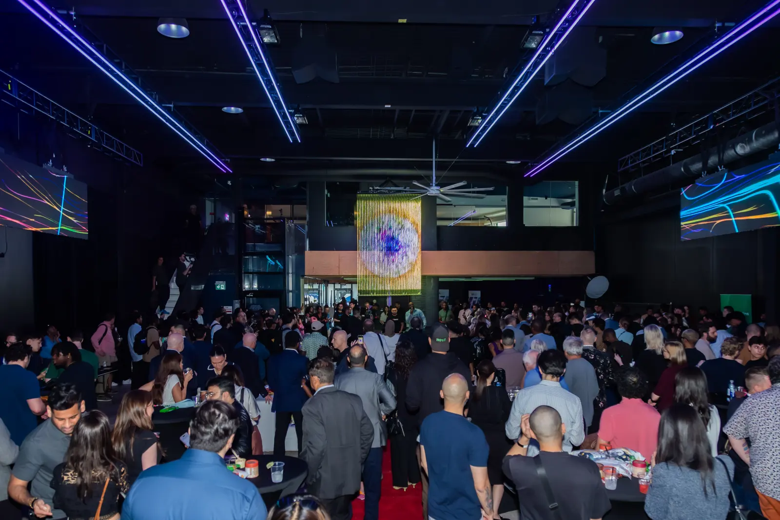 Crowd at the evening mixer beneath colorful projected visuals