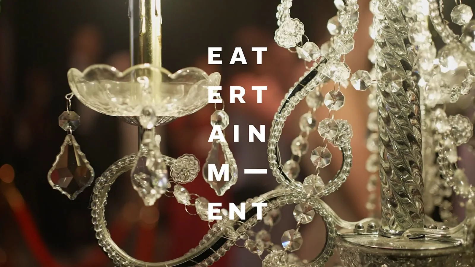 Eatertainment title card over a crystal chandelier at a candlelit event